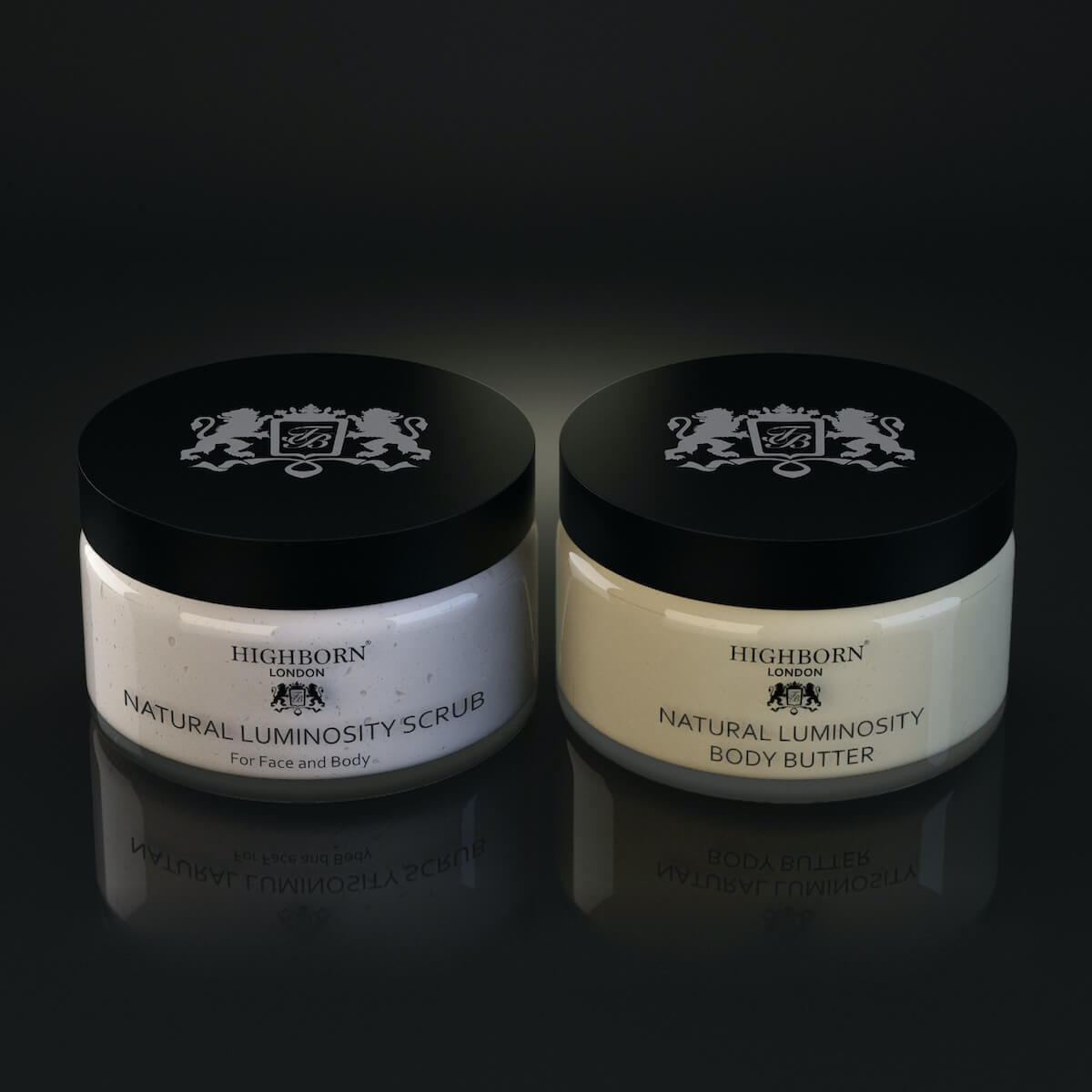 Highborn London Natural Luminosity Scrub and Body Butter jars with black lids on dark reflective surface